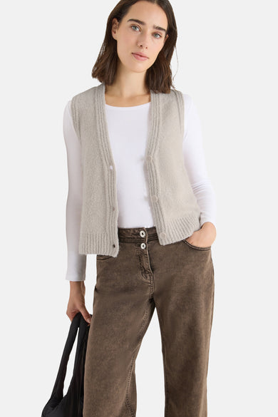 Beige tanktop van CECIL, gedragen over een wit T-shirt met lange mouwen, met een bruine jeans en een zwarte tas.