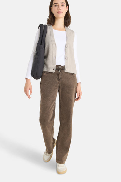 Débardeur beige par CECIL, porté sur un t-shirt blanc à manches longues, avec un jean marron et un sac noir.
