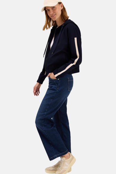 Korte blauwe jas van CECIL, met witte strepen op de mouwen, gedragen met een blauwe jeans en beige sneakers.