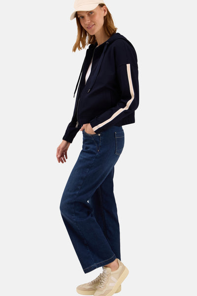 Korte blauwe jas van CECIL, met witte strepen op de mouwen, gedragen met een blauwe jeans en beige sneakers.