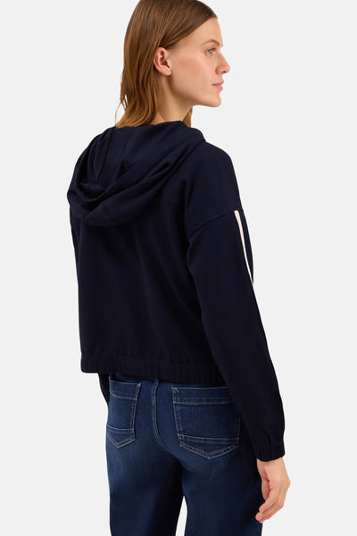 Korte blauwe jas van CECIL met capuchon en streepdetail op de mouw, gedragen met een spijkerbroek.