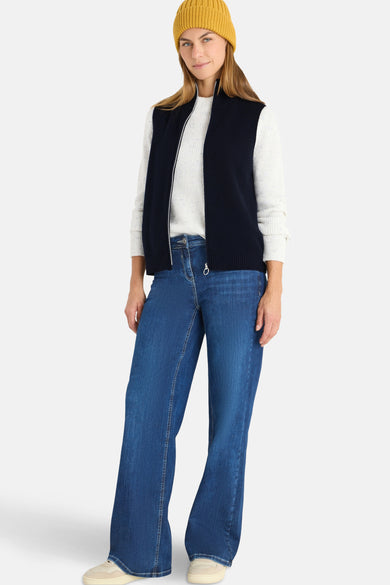 Blauwe tanktop van CECIL, gedragen met een witte trui, een gele muts en een wijde jeans.