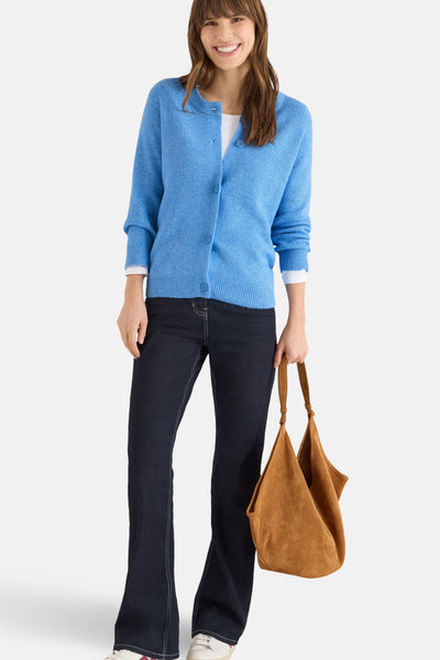 Blauwe CECIL-cardigan, gedragen over een wit T-shirt, met een uitlopende spijkerbroek en een bruine suède tas.