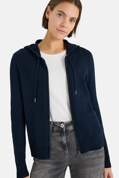 Blauwe cardigan van CECIL, gedragen over een wit T-shirt, met een grijze jeans en zilveren sneakers.