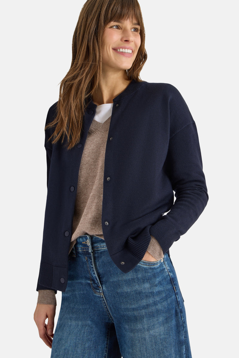 Marineblauwe cardigan van CECIL, gedragen over een beige trui en een wit T-shirt, met een blauwe jeans.