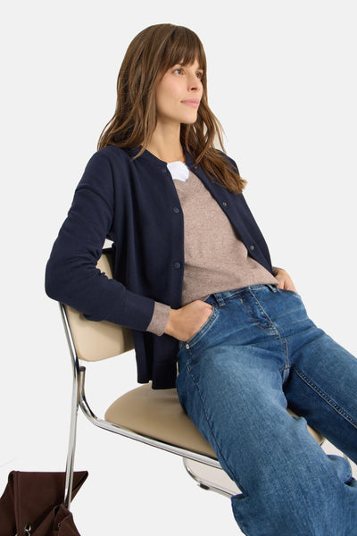 Cardigan bleu marine de CECIL, porté sur un pull beige et un t-shirt blanc, avec un jean bleu.
