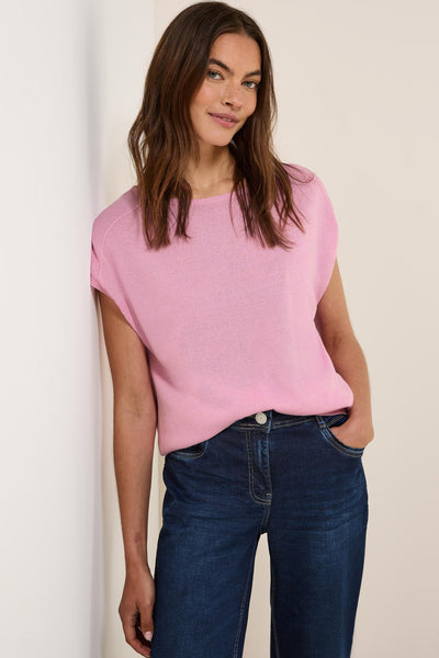 Pull à col rond rose de CECIL, porté avec un jean bleu foncé et posant contre un mur clair.
