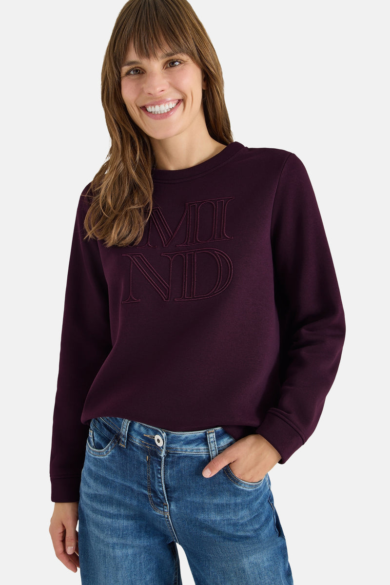 Mauve CECIL sweatshirt met toon-op-toon borduurdetails, gedragen met een wijde blauwe jeans en bruine sneakers.
