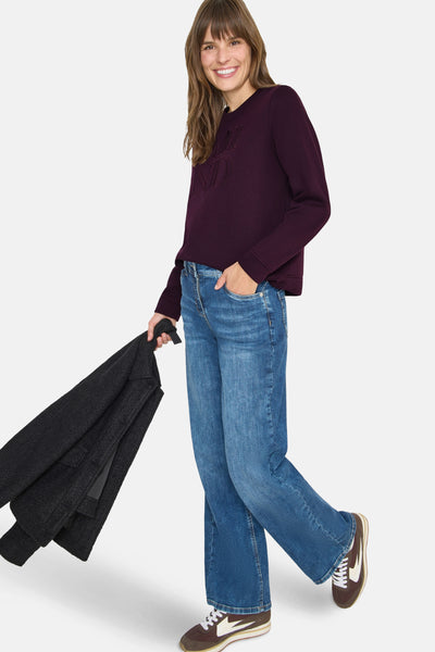 Sweat mauve CECIL avec détails de broderie ton sur ton, porté avec un jean bleu ample et des baskets marron.
