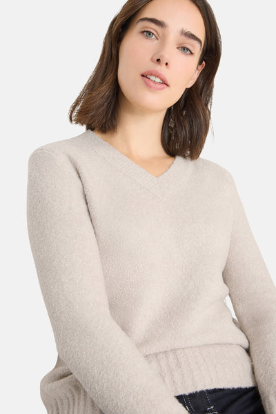 Pull col V beige de CECIL, en maille douce et duveteuse, porté avec un pantalon foncé.
