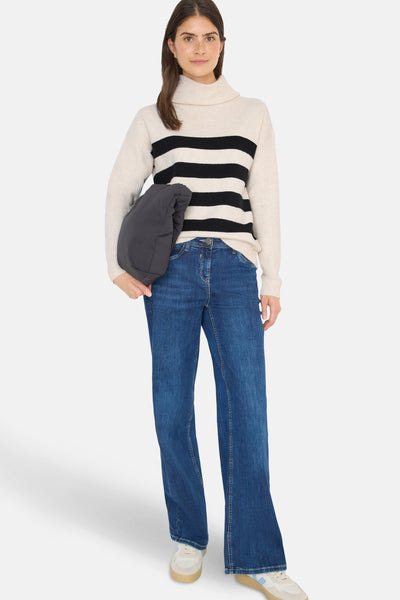 Pull rayé multicolore de CECIL porté avec un jean bleu et des chaussures de sport.