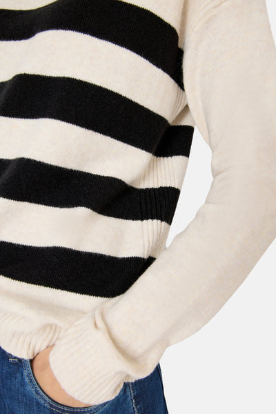 Pull multicolore de CECIL à rayures horizontales noires et écrus, porté avec un jean bleu.