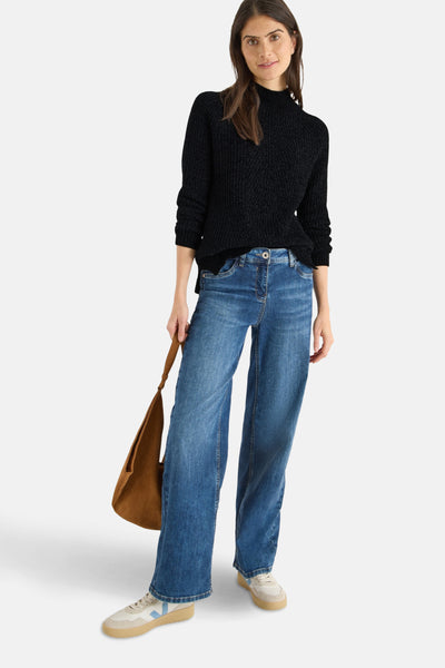 Pull à col roulé noir de CECIL, porté avec un jean ample bleu et un sac à main marron.
