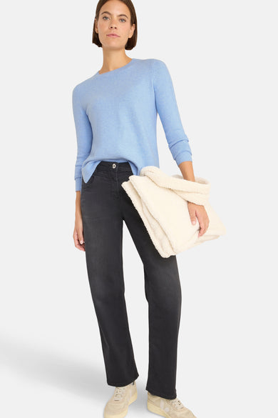 Pull ras du cou bleu de CECIL, porté avec un pantalon noir et un sac en fausse fourrure crème.

