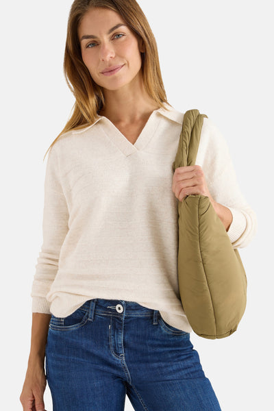 Beige trui met polokraag van CECIL, gedragen met een blauwe jeans en een olijfgroene gewatteerde tas.