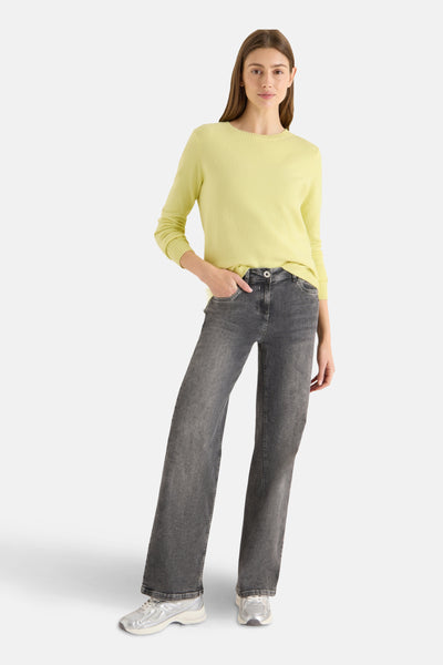 Pull à col rond jaune de CECIL, porté avec un jean gris délavé et des baskets argentées.