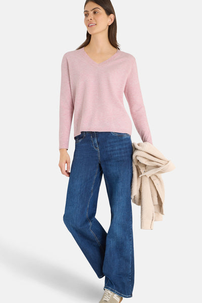 Pull rose à col en V de CECIL, porté avec un jean bleu ample et une veste en sherpa beige.
