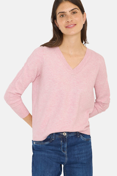 Roze V-hals trui van CECIL, gedragen met een donkerblauwe jeans en handen achter de rug.