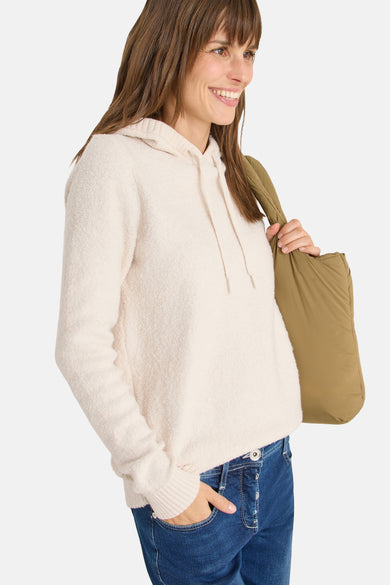 Pull à capuche écru de CECIL, porté avec un jean bleu et un sac souple kaki.