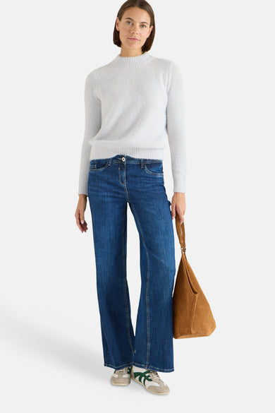 Pull col montant gris de CECIL, porté avec un jean évasé et un sac à main en daim marron.
