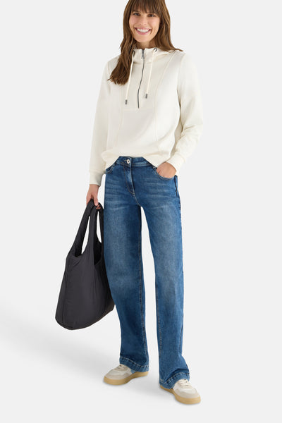 Sweat à capuche écru de CECIL, avec capuche à cordon et fermeture éclair, porté avec un jean bleu et un sac noir.