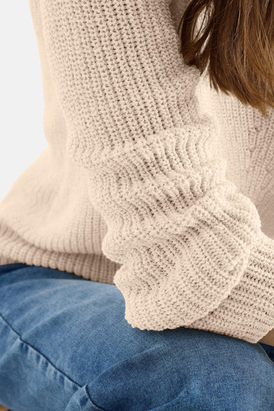 Pull col V beige de CECIL, en maille épaisse texturée, porté avec un jean bleu.
