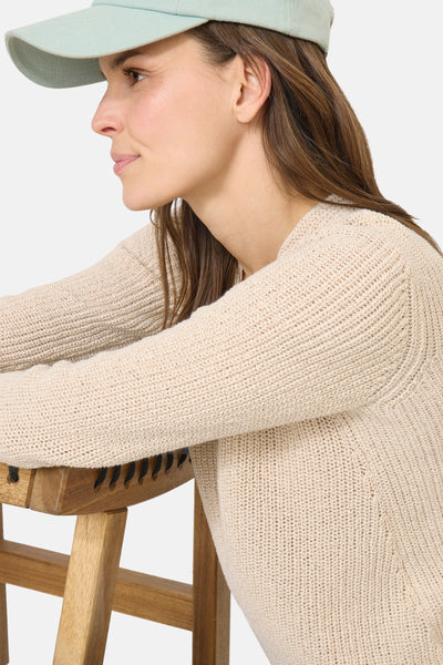 Pull col V beige de CECIL, en maille tricotée avec détail côtelé, porté avec une casquette vert d'eau.
