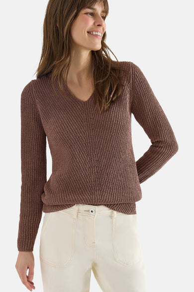 Pull col V brun de CECIL, en tricot à mailles, porté avec un pantalon blanc.