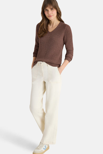 Pull col V brun de CECIL, en maille côtelée, porté avec un pantalon large écru et des baskets blanches.

