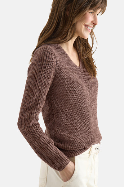 Pull col V brun de CECIL, en maille texturée, porté avec un pantalon blanc.
