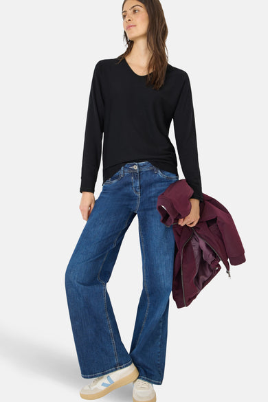 Pull col rond noir de CECIL, porté avec un jean évasé et une veste bordeaux.