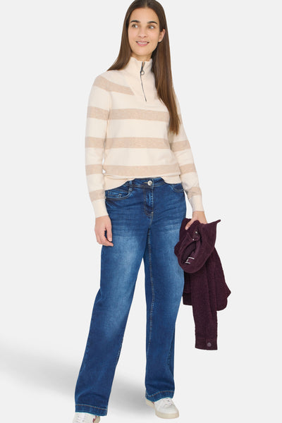 Pull beige à rayures horizontales par CECIL, porté avec un jean bleu ample et des baskets blanches.