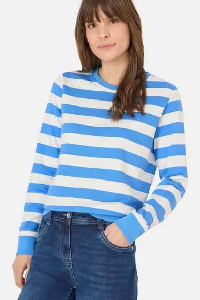 Blauwe gestreepte trui van CECIL, gedragen met een donkere jeans, een lachende vrouw op de achtergrond.