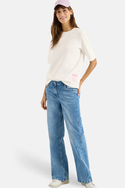 T-shirt blanc à manches courtes de CECIL, avec un logo rose discret, porté avec un jean et une casquette.

