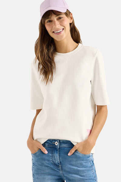 T-shirt blanc à manches courtes de CECIL, porté avec un chapeau rose et un jean bleu.

