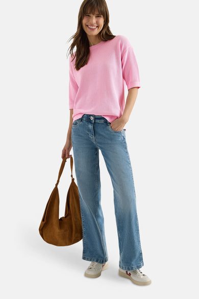 Pull rose de CECIL porté avec un jean évasé et un sac en daim marron.
