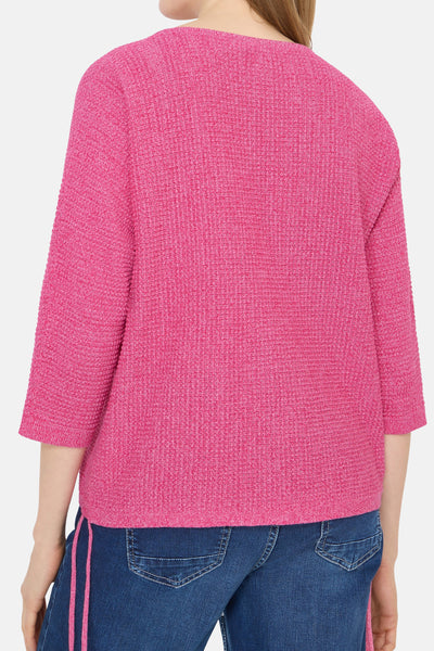 Pull rose en maille texturée de CECIL, manches trois-quarts, porté avec un jean bleu à rayures roses.
