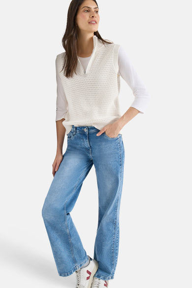 Gilet blanc en maille by CECIL, porté sur un haut à manches trois-quarts et un jean décontracté.
