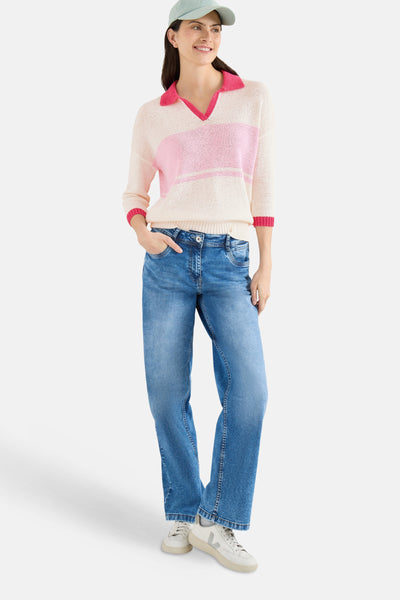 Pull col V multicolore de CECIL avec rayures roses et coupe décontractée, porté avec un jean bleu et des baskets blanches.
