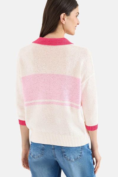 Pull en maille multicolore par CECIL, avec des rayures roses et porté avec un jean bleu.
