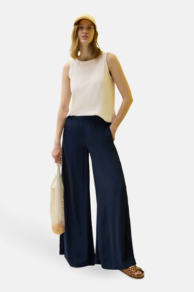 Beige mouwloos top van CECIL, gedragen met een marineblauwe wijde broek en een beige hoed.