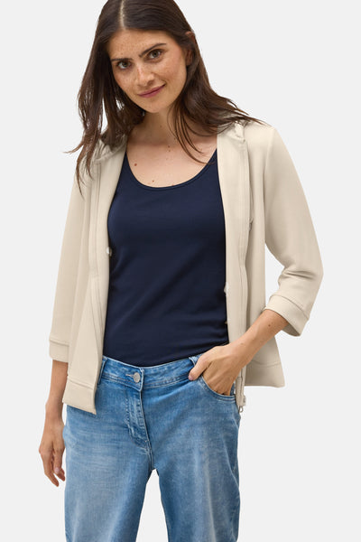 Beige vest van CECIL gedragen met een marineblauwe tanktop en een lichtblauwe spijkerbroek.