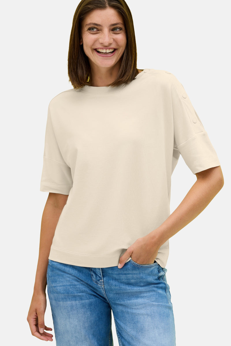 Beige T-shirt met korte mouwen van CECIL, met decoratieve knopen op de korte mouwen en gedragen met een blauwe jeans.