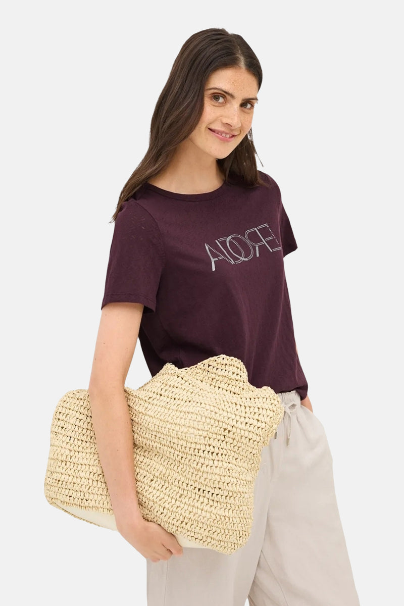 Bordeaux T-shirt met korte mouwen van CECIL, gedragen met een lichte broek en een rieten tas.
