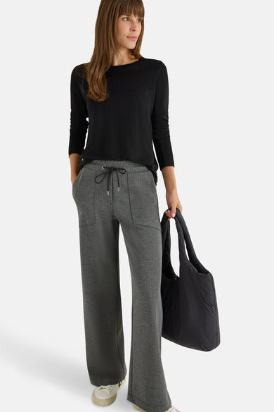 T-shirt à manches longues noir de CECIL, porté avec un pantalon gris à motif à chevrons et un sac noir.