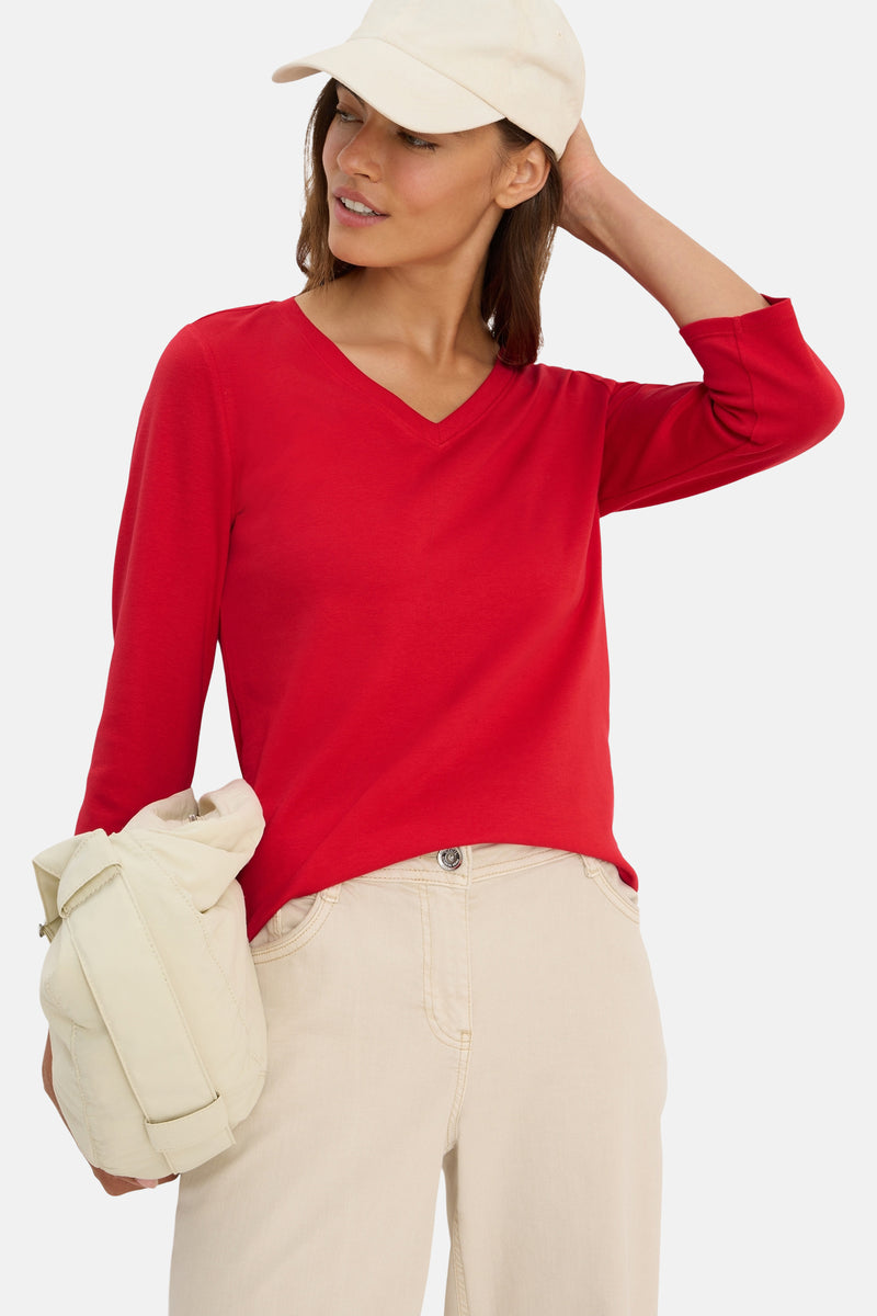 Rood T-shirt met lange mouwen van CECIL, gedragen met een beige broek en een pet.