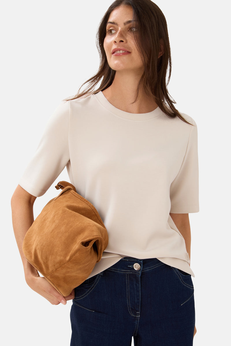 Top met korte mouwen beige van CECIL, gedragen met een donkerblauwe jeans en een bruine suède tas.