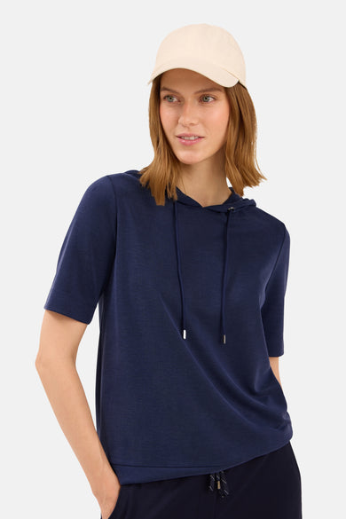 Sweat à capuche bleu de CECIL, avec cordon de serrage et porté avec une casquette beige.