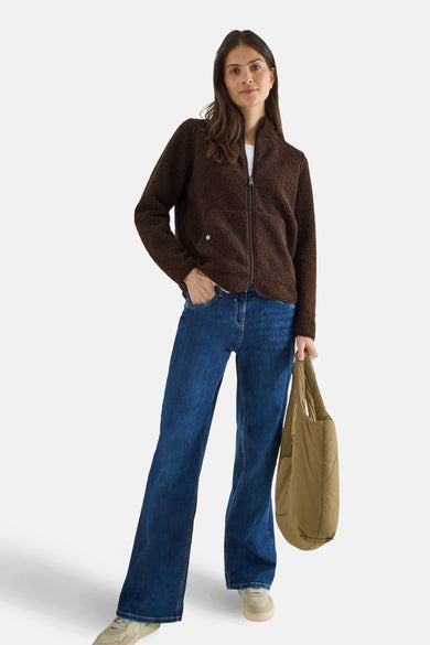 Veste courte marron en polaire de CECIL, portée avec un jean bleu et un sac à main kaki.
