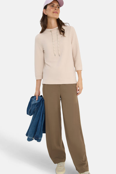 Beige 3/4-mouwen T-shirt van CECIL, met trekkoord en gedragen met een bruine broek en een blauwe spijkerjas.
